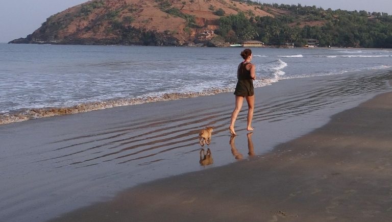 Vrouw wandelt met een hond langs zee