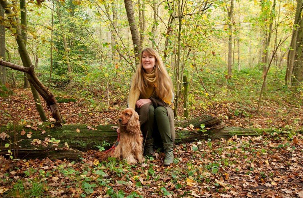 Vrouw zit met haar hond in het bos