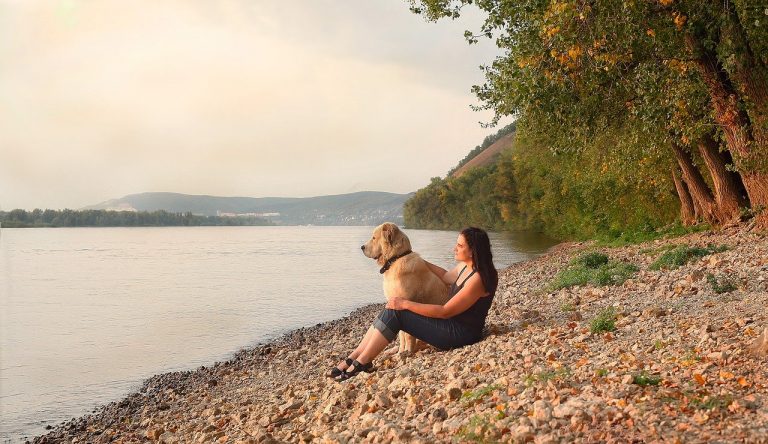 Vrouw zit met haar hond aan het water