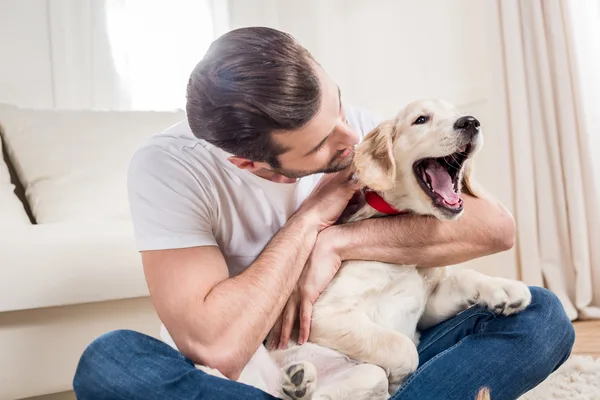 Man zit met een jonge Golden Retriever op zijn schoot